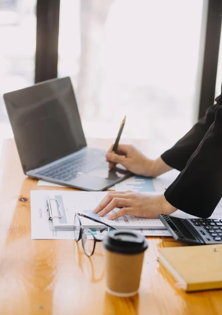 dipendente seduta alla scrivania che lavora al computer con blocco di fogli per prendere appunti